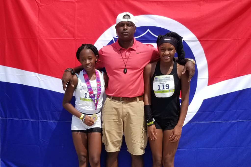 El presidente del L-D23, Carlos Brooks, es entrenador de atletismo infantil en sus horas libres. Brooks se encuentra de pies con sus hijas, Adrianna, a la izquierda, y Aryanna. Ambas chicas son estrellas de atletismo en <em>Amateur Athletic Union</em> y <em>USA Track</em>.