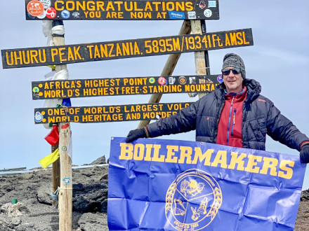 Dave Gototweski celebra con una bandera del Local 13 en la cima del Monte Kilimanjaro.