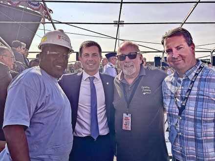 El presidente del Local 19, James Hall, a la izquierda, celebra el bautizo del Patriot State con el secretario de transporte de los Estados Unidos, Pete Buttigieg, segundo desde la izquierda. 