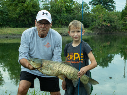 El vicepresidente internacional Fultz ayuda a un joven pescador a sujetar la mayor captura del día.