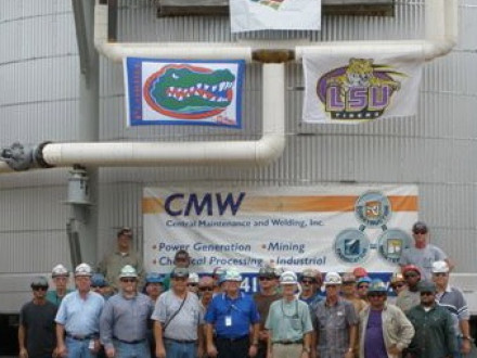 Members of Louisiana L-37 and Florida L-433 stand in front of a converter they built, displaying flags of their favorite college teams.