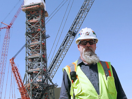Main steward Bob Furnish stands below the unit 1 tower at Ivanpah. The boiler sits atop the tower and is coated with a black, heat-absorbing material.  Photo by Chris Farina Photography