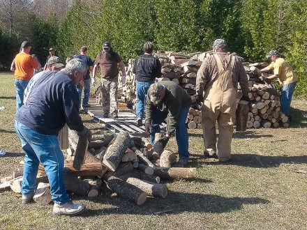 Local D351 members and other volunteers stack wood for Wayne Woloszyk in Posen, Mich.