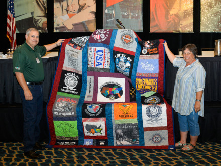 JoBeth Allison displays the quilt she made to support the Disaster Relief Fund. At left is Director of Health and Safety Services Mark Garrett.