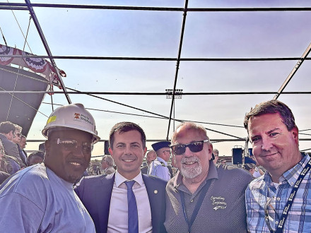 Local 19 President James Hall, left, celebrates the christening of the Patriot State with U.S. Secretary of Transportation Pete Buttigieg, second from left. 