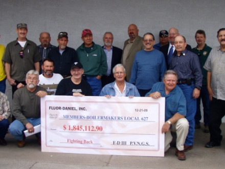 Local 627 members display a mock check representing their portion of a $12 million settlement with Fluor Daniel. Joining in the presentation are, standing, BM-ST Allen Meyers, third from right; Blake & Uhlig attorney Mike Stapp, fourth from right; D-CRS/AIP Gary Evenson, seventh from right; and IST Bill Creeden, eighth from right.
