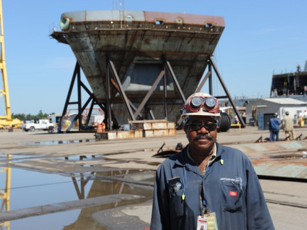 L-1814 President Chris Burnett stands near the bow section of an LPD ship under construction at the Avondale shipyard in 2009.