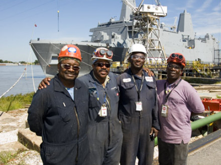 Four L-1814 members who lived at Camp Katrina stand before the USS New York. L. to r., Jorge Martinez; Chris Burnett, lodge president; Ricky Washington; and Harold Brown.