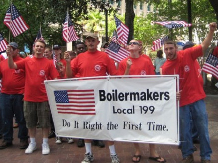 Holding a banner at the Jacksonville, Fla., Flag Day parade with SAJAC instructor Eric Olson (second from left) are first-year apprentices (l. to r.) Glen Wiley, Matt Hersey, and Warren Bush.