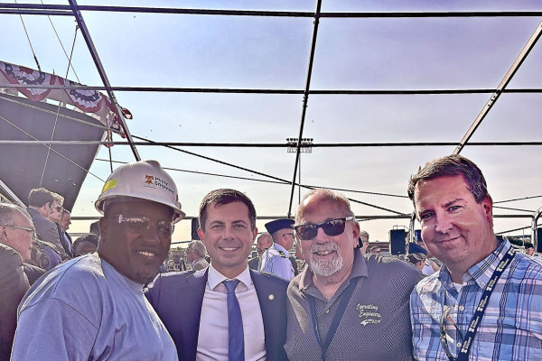 Local 19 President James Hall, left, celebrates the christening of the Patriot State with U.S. Secretary of Transportation Pete Buttigieg, second from left. 