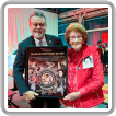 IVP-WS J. Tom Baca entrega a Marian Parsons Wynn una placa en honor a su trabajo como boilermaker en los astilleros Kaiser durante la Segunda Guerra Mundial y con el Rosie the Riveter Trust.
